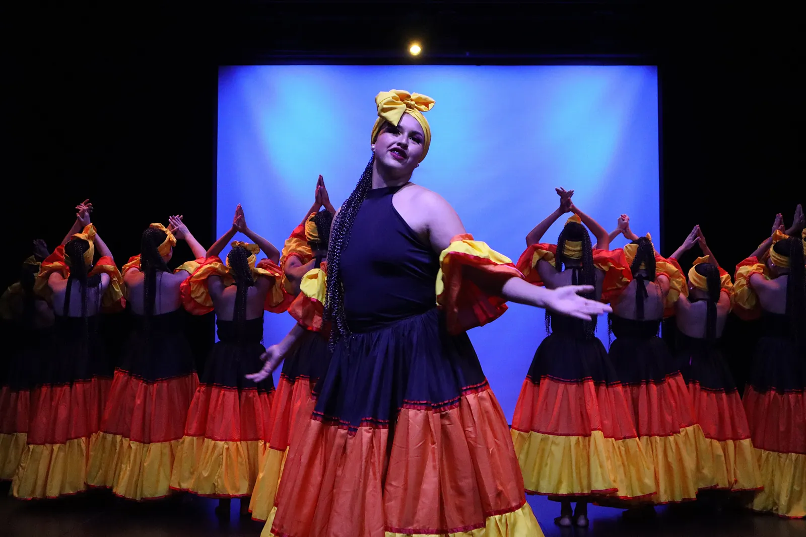 Bailarina en escena con vestido tradicional naranja y amarillo